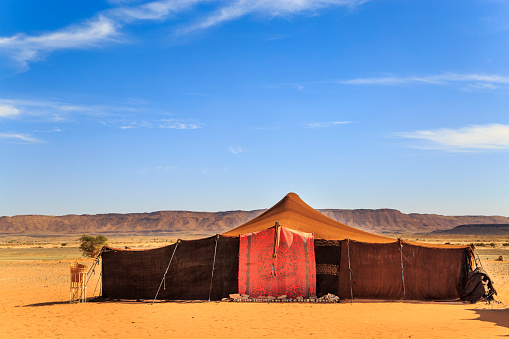 Nomad tents made of camel skin in the middle of the desert with mountains in the background