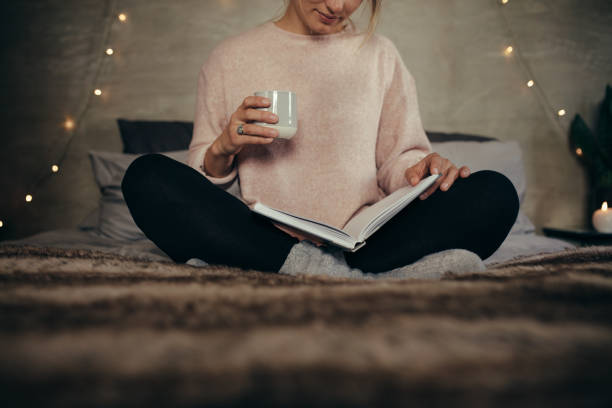 istock Woman reading book on bed at home 901324210