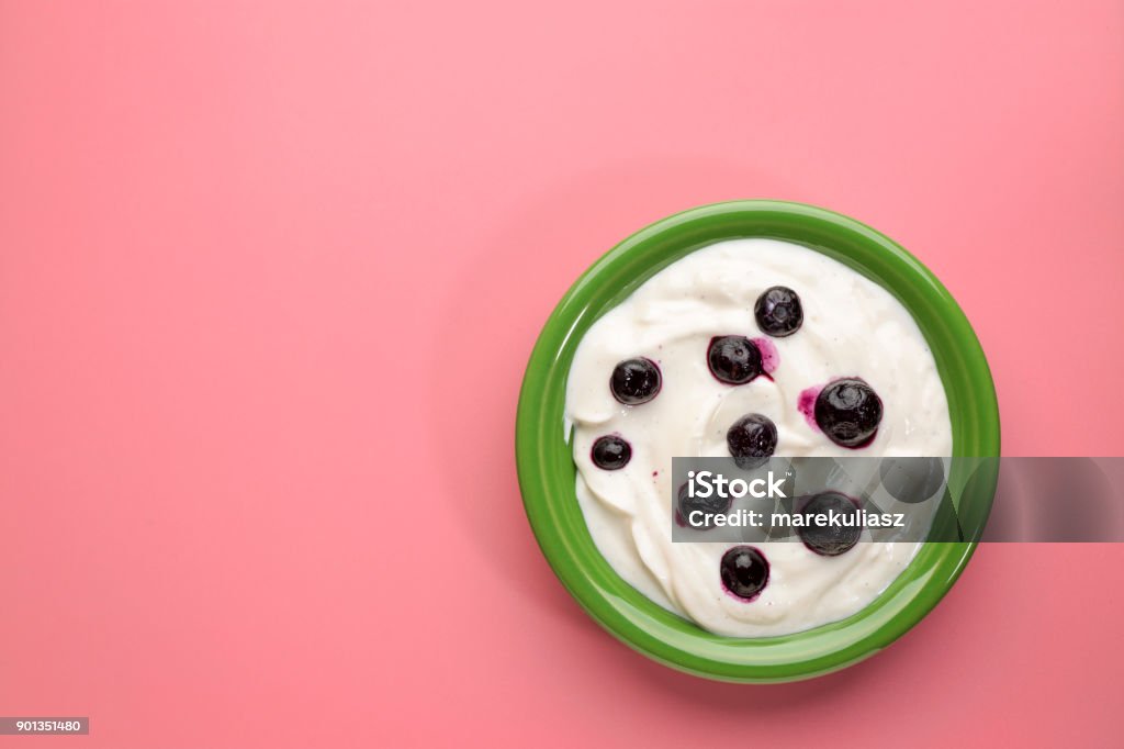 bowl of Greek yogurt with vanilla and blueberries live organic Greek yogurt with vanilla and blueberries in a green ceramic bowl against pink background Cut Out Stock Photo