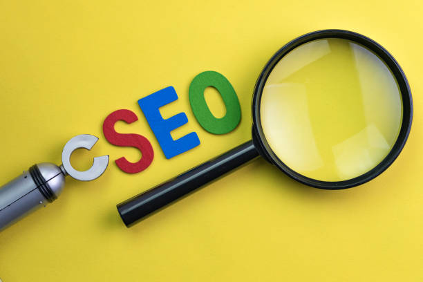istock Magnifying glass, alphabet abbreviation SEO and robot arm on vivid yellow background using as SEO Search engine optimization concept 901359500