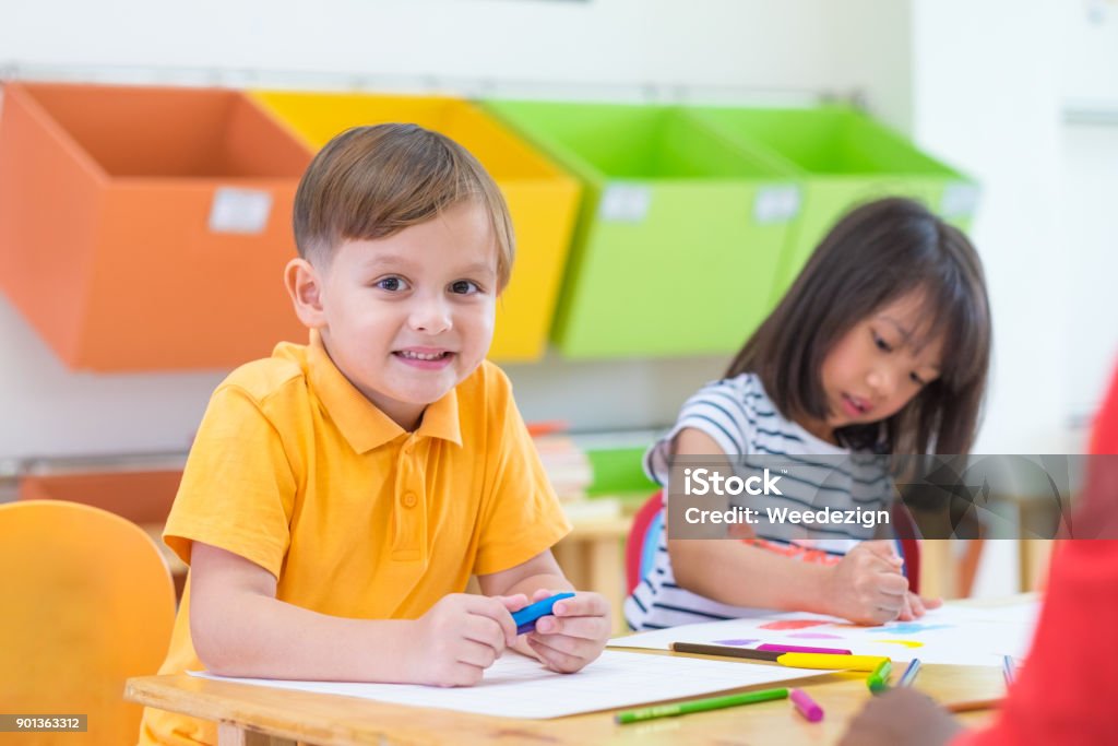 Caucasian boy ethnicity kid smiling white learning in classroom with friends and teacher  in kindergarten school, education concept. Caucasian boy ethnicity kid smiling white learning in classroom with friends and teacher  in kindergarten school, education concept Boys Stock Photo
