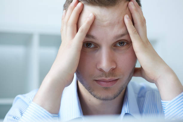 istock Feeling tired. Tired man being overloaded at work with many tasks. Businessman being depressed by working in office. Frustrated young handsome man looking exhausted while sitting at his working place. 901363542