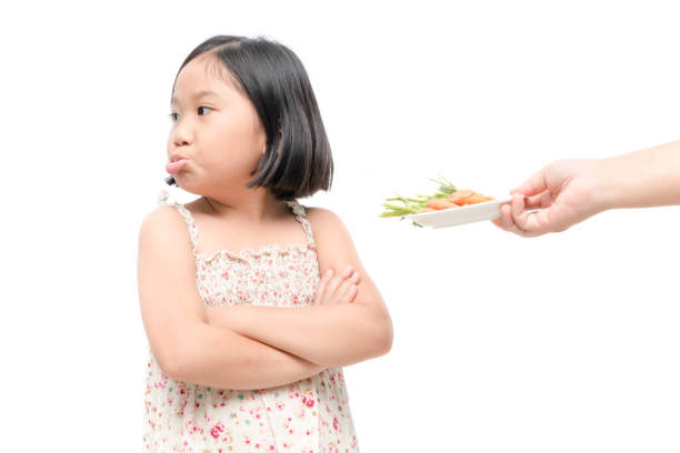 asian child girl with expression of disgust against vegetables isolated on white background asian child girl with expression of disgust against vegetables isolated on white background, Refusing food concept funny plates stock pictures, royalty-free photos & images