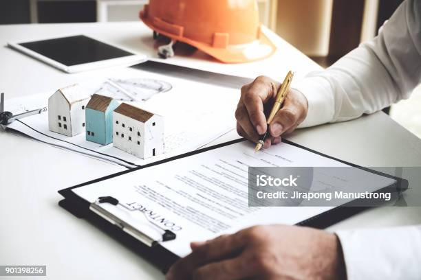 Businessmen Are Checking The Contract To Use The Right Pen Signed Building Approval With Blueprint And House Model On The Table Stock Photo - Download Image Now