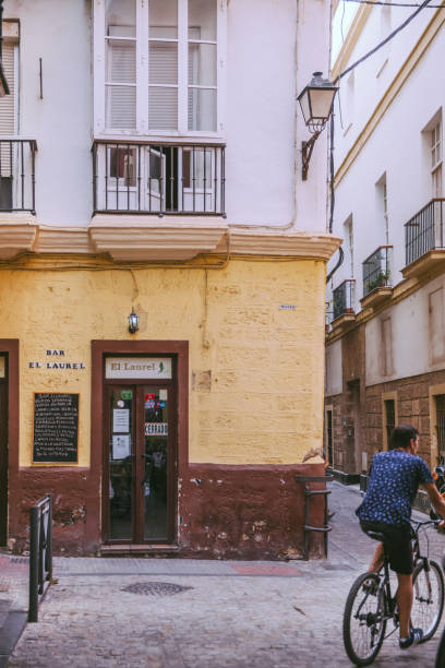 Cadiz, Spain - September 14th, 2017: Locals walk down a cobble street  in the background through a mixed commercial and residential district in Cadiz,Spain. Cadiz is considered to be the oldest city in Western Europe.