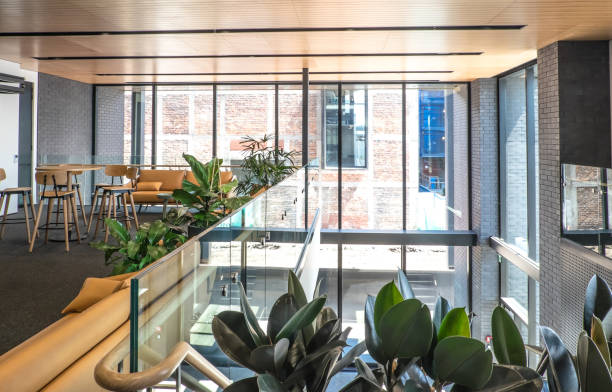 istock Vestibule in a modern open plan office building - airy bright interior design with large glass windows in background, plus meeting area with stools, couch and sofa 901404992