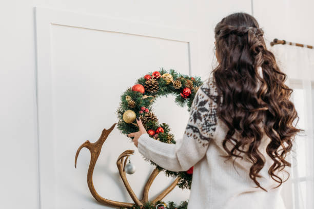 istock woman hanging christmas wreath over fireplace 901415606