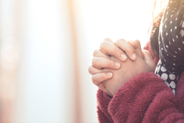 istock Woman hands folded in prayer in beautiful nature pine tree park with sunlight 901417380