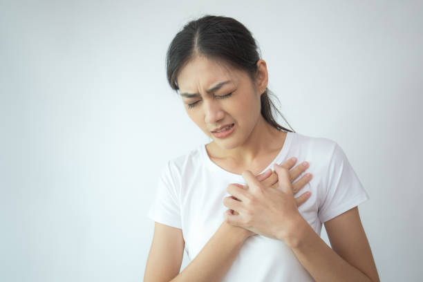 woman touching her chest with hands. young asian woman feel pain in her chest . isolated on white background. - chest pain imagens e fotografias de stock