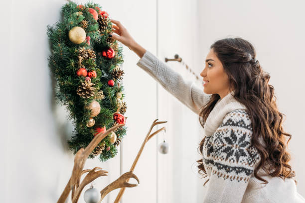 istock woman hanging christmas wreath over fireplace 901424780
