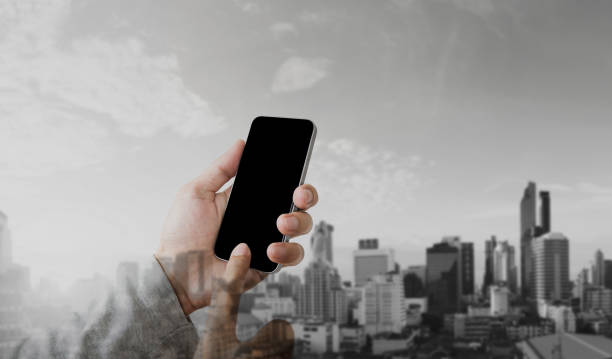 istock Businessman hand using mobile smart phone with double exposure modern city background, blank black screen 901429404
