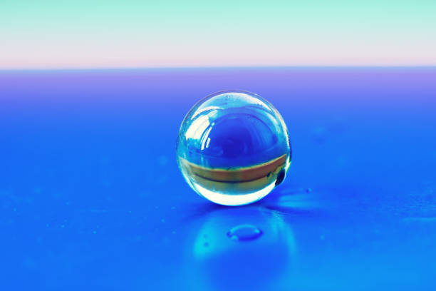 istock Transparent glass bead closeup on a bright blue cardboard surface, 901429440