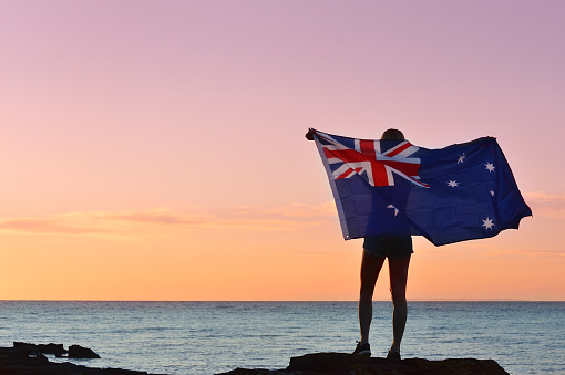 Waving the Australian Flag, evening summer light on a beach.