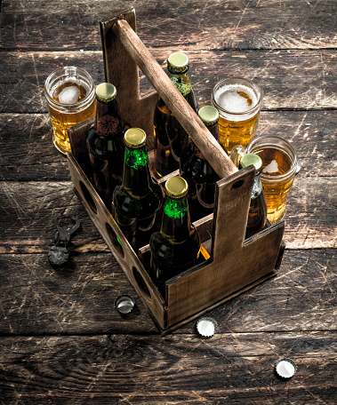 Bottles with beer in an old box. On a wooden background.