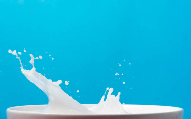 istock Splash of milk from a cup on blue background. 901439906