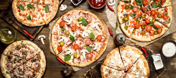 Varied pizzas with sauce. On a wooden table.