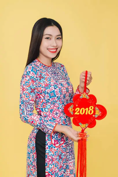 Attractive Vietnamese woman wearing traditional costume, isolated on yellow background