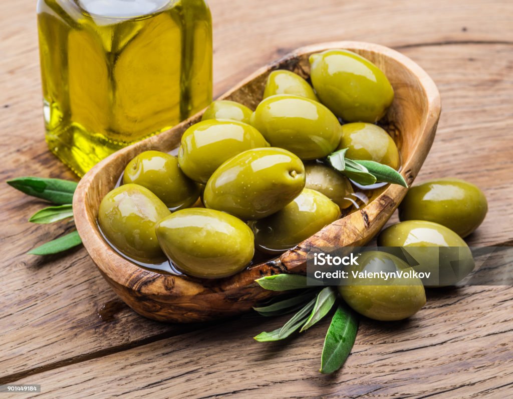 Olive berries and bottle of olive oil on the wooden table. Green Olive Fruit Stock Photo