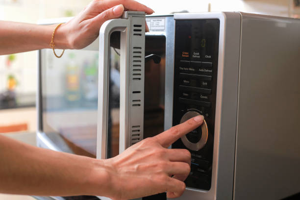 Woman's Hands Closing Microwave Oven Door And Preparing Food in microwave. stock photo