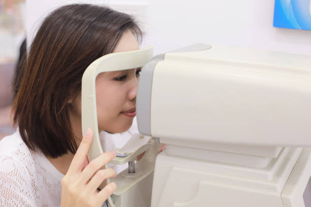 Woman doing eye test with optometrist mechine in medical office. stock photo