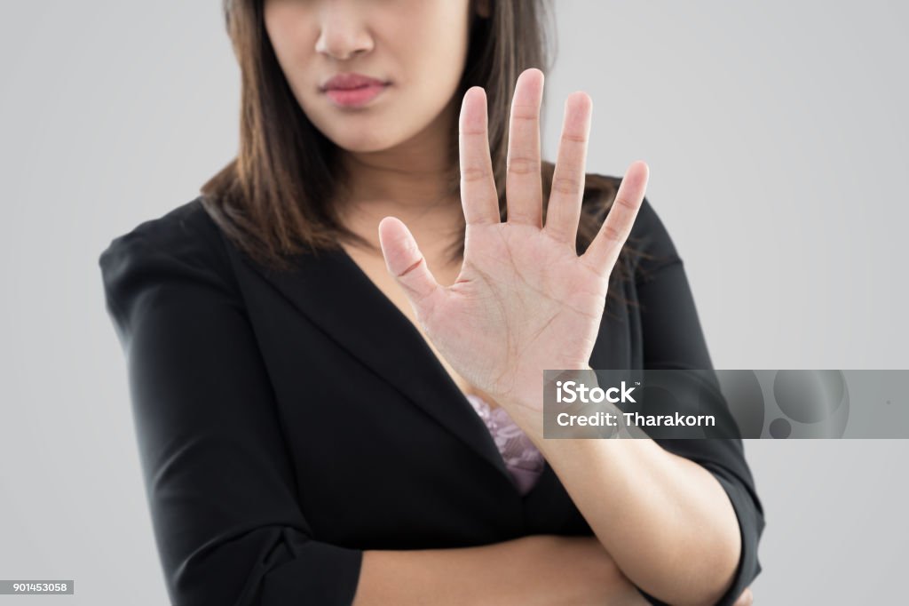 Denial Business woman in black suit showing her denial with no on her hand against gray background Denial Stock Photo