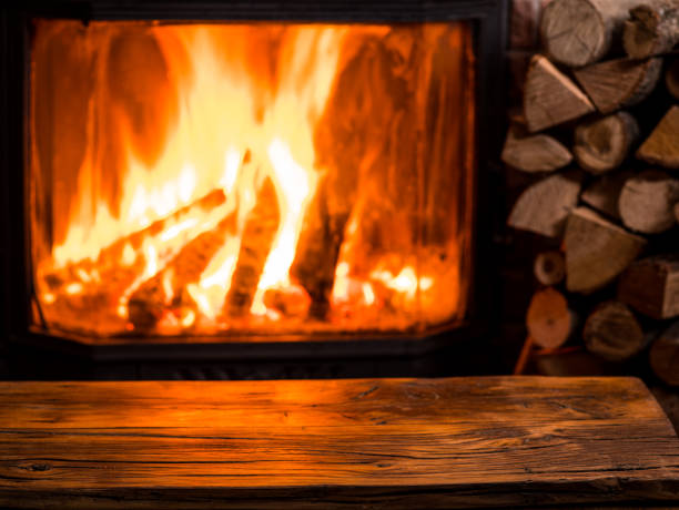 istock Old wooden table and fireplace with warm fire at the background. 901456678