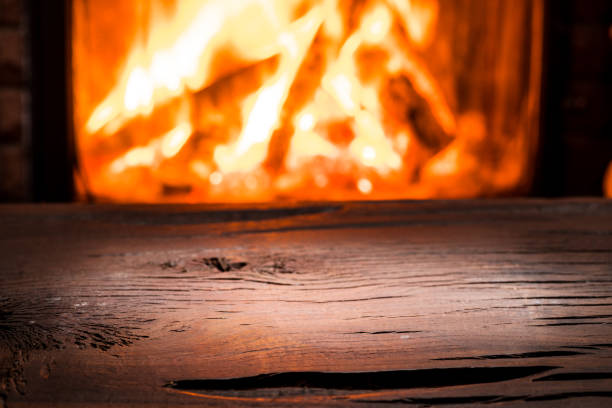 istock Empty wooden table and fireplace with warm fire on the background. 901464586