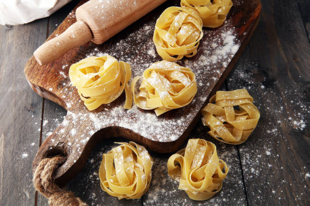 istock Making homemade pasta linguine on rustic kitchen table with flour, rolling pin and pasta 901476894