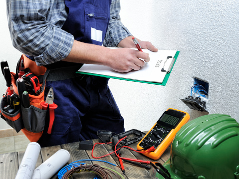 Young electrician takes notes while working in a residential electrical installation