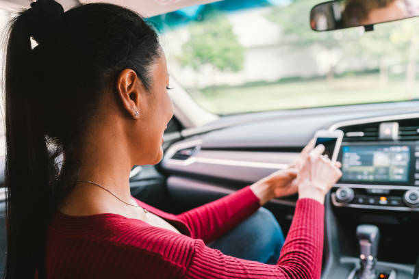 現代の車でスマート フォンのアプリを使用しての女性。携帯電話アプリケーション、地図ナビゲーション デバイス技術、輸送、またはクラウドソーシング タクシー コンセプト - urbanscape ストックフォトと画像