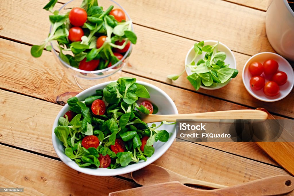 Cherry tomatoes and basil salad on a plate with a pot on a woode Cherry tomatoes and basil salad on a plate with a pot on a wooden table. Basil Stock Photo