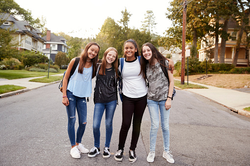 Teen girls on the way to school look to camera, full length