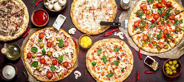 variety of pizzas with sauces. On a rustic background.