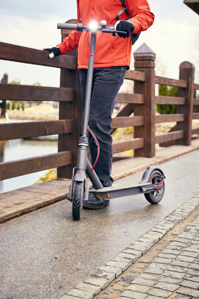istock A man in a red jacket with a backpack and a scooter on the street. 901496706