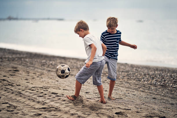 ビーチでサッカー少年 - beach football ストックフォトと画像