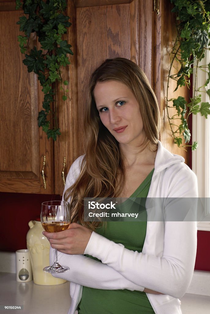 young woman with a glass of wine in her kitchen  Adult Stock Photo