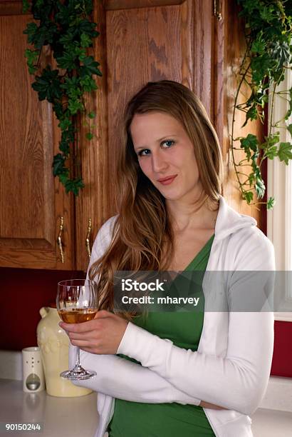 Young Woman With A Glass Of Wine In Her Kitchen Stock Photo - Download Image Now - Adult, Alcohol - Drink, Cabinet