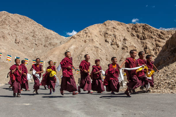 grupa szczęśliwych buddyjskich dzieci biegających do świątyni. - india mountain child people zdjęcia i obrazy z banku zdjęć