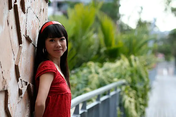 Photo of girl in red top standing beside a wall