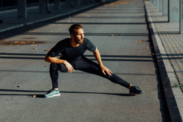 istock Young man stretching legs outdoors 901522576