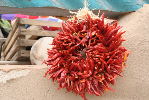 Chili peppers are suspended on a rope on a wooden background. Red hot pepper hanging on a dark background. Spicy food. Seasonings for cooking.