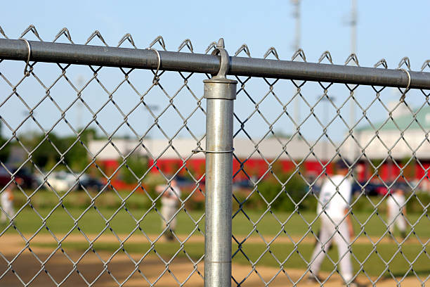 Chainlink fence surrounding baseball game stock photo