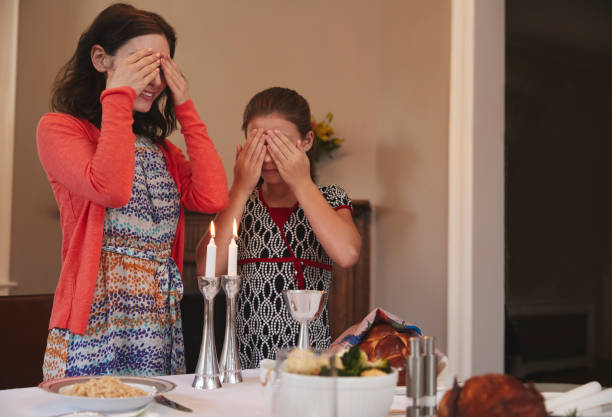 fille juive et mère couvrent les yeux de réciter la bénédiction de shabbat - challah jewish sabbath photography candle photos et images de collection