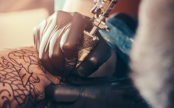 istock Tattoo master making tattoo on customer's leg 901527014