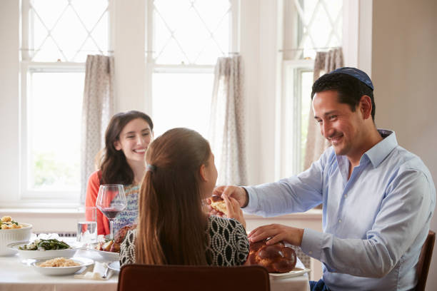 homme juif pain challah de partage avec la famille au repas de chabbat - seder passover judaism family photos et images de collection