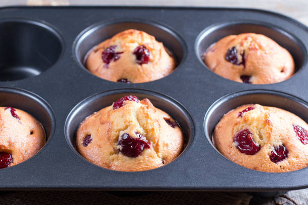 istock Homemade muffins with cherry in a baking form on a wooden background 901538312
