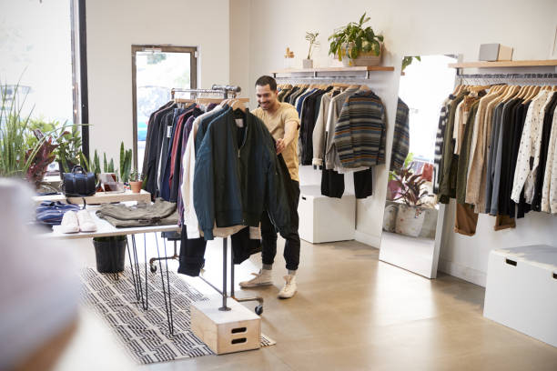 istock Young Hispanic man browsing through clothes in a shop 901542582
