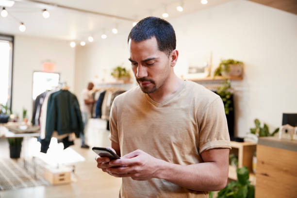 istock Young Hispanic man using smartphone in a clothes shop 901542600