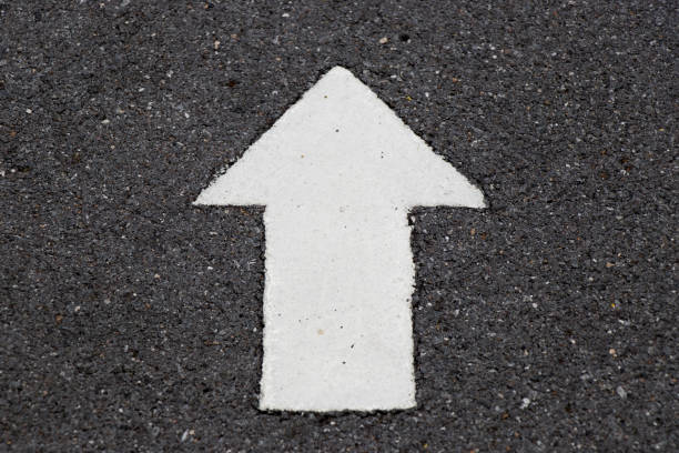 istock White painting in forward direction arrow symbol on black asphalt road background 901545424