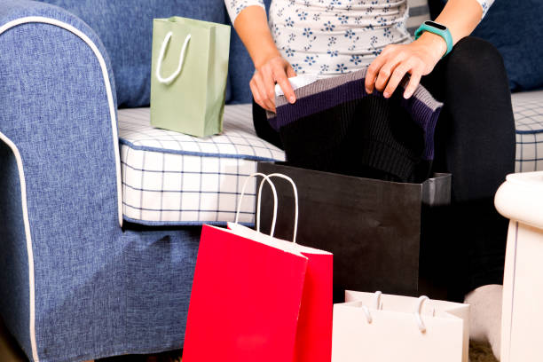 istock woman sitting on the sofa with the shopping bag is checking purchasing 901545896